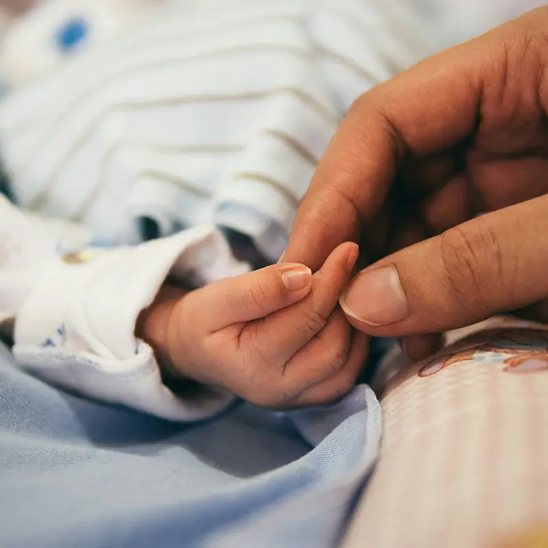 Parent holding newborn's hand